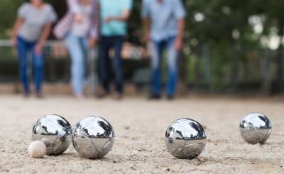 Four adults playing a game of pétanque